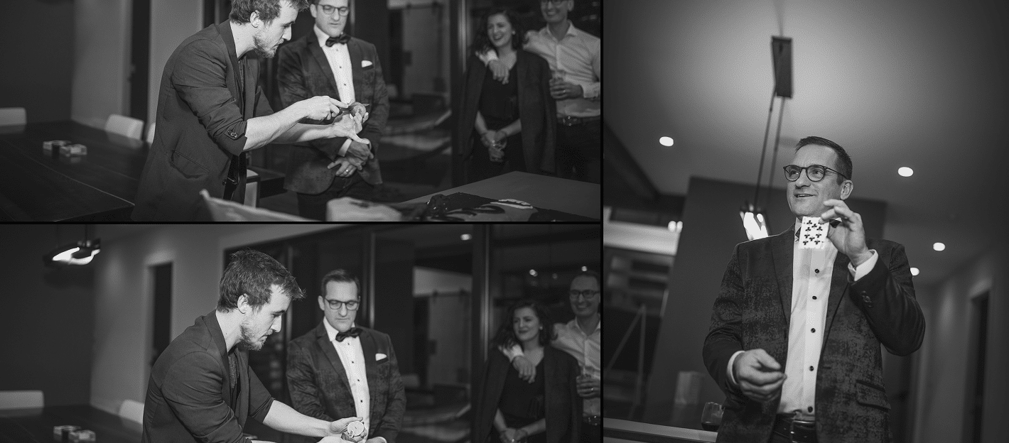 A magician performs card tricks in a stylish setting, engaging a small audience. One person is showing a card while others watch attentively, creating an atmosphere of intrigue and entertainment.