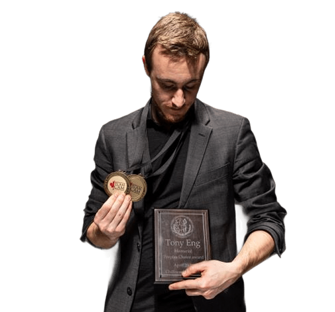 A man in a suit holds two medals and a wooden plaque with the name "Tony Eng" displayed on it.