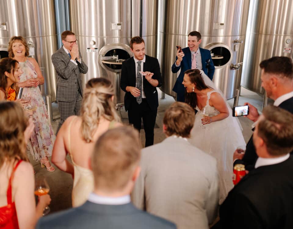 A group of people at a wedding, gathered around a card trick performer.