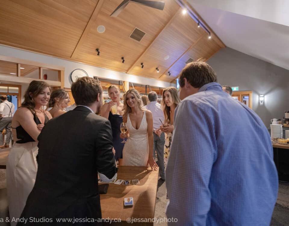 A group of people socialize and enjoy drinks at a stylish indoor venue, featuring wood accents and a well-lit bar area.